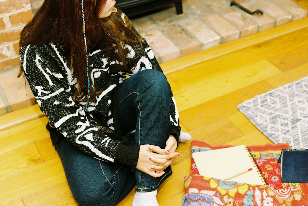 Brazilian woman writing thoughtfully in a journal at a sunlit desk at home